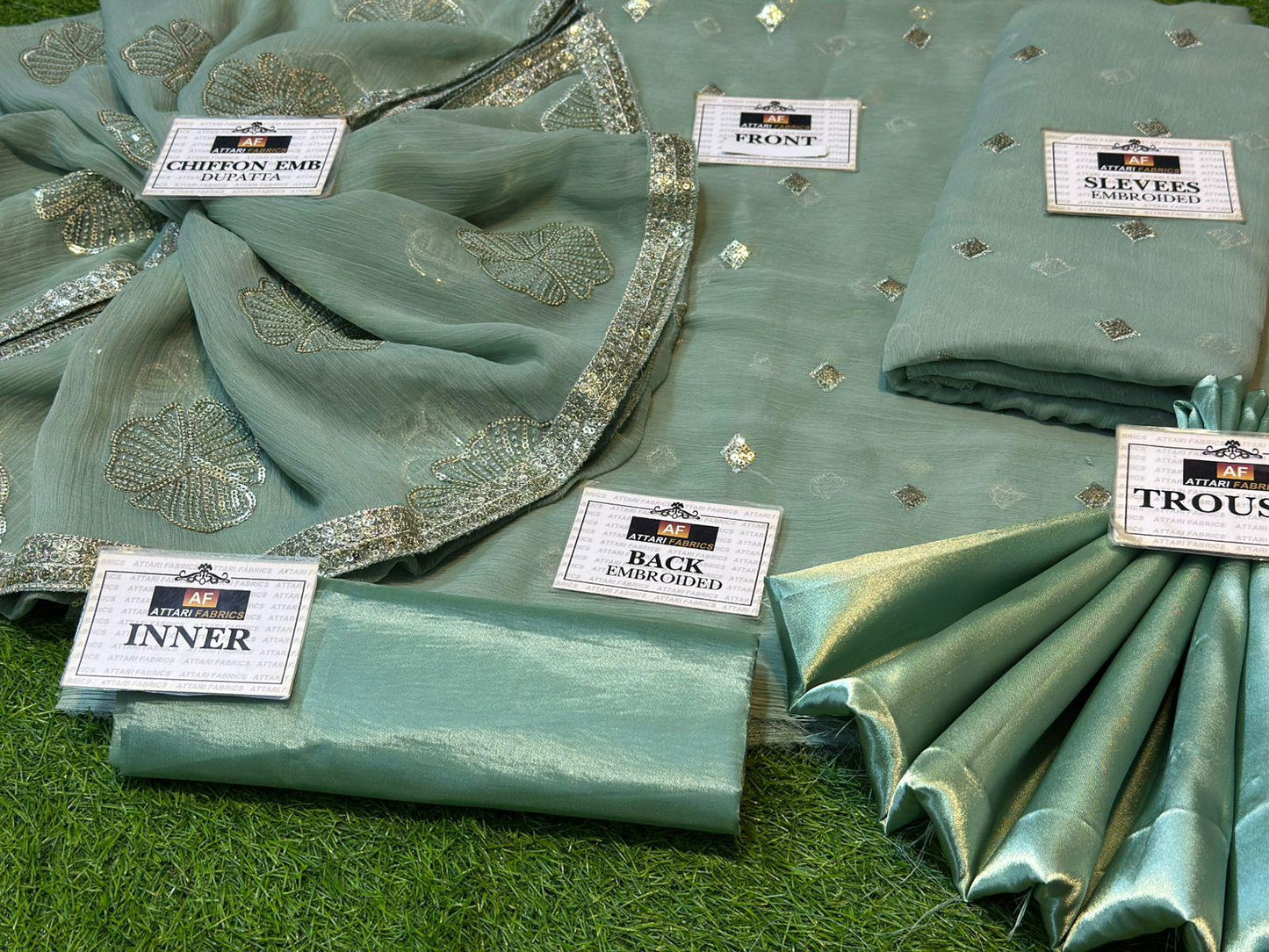 Teal fabric with embroidered details on a green surface