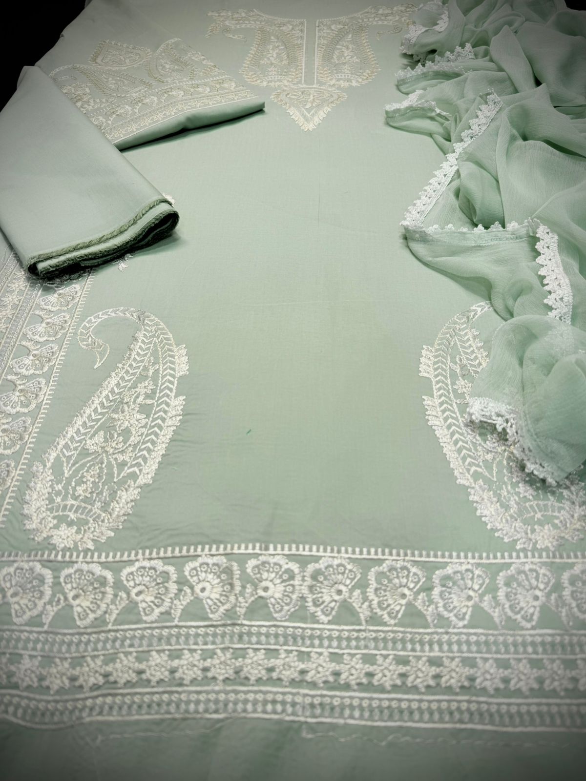 Light green fabric with white lace patterns on a flat surface