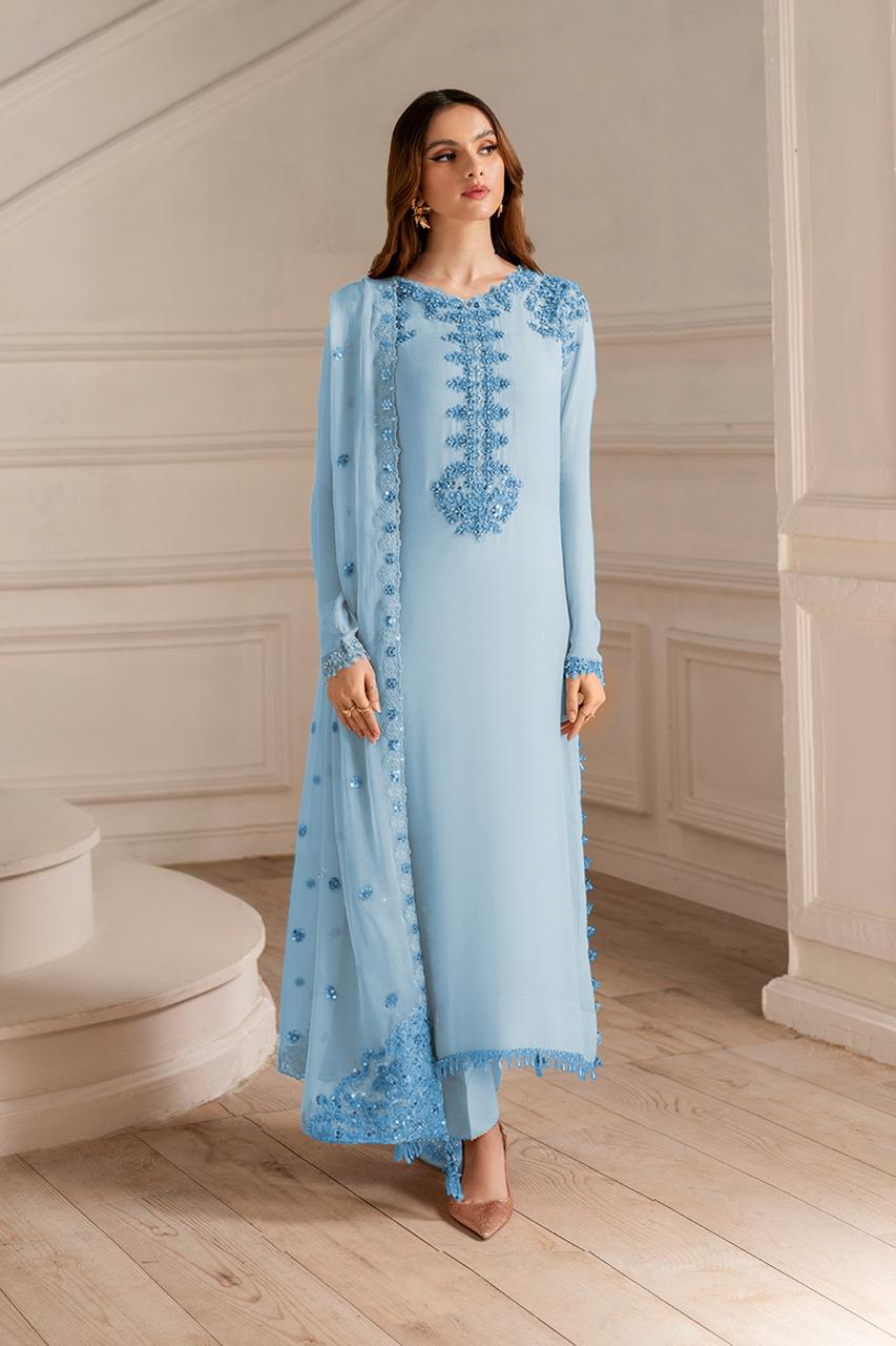 Woman wearing a light blue embroidered outfit in an elegant room.