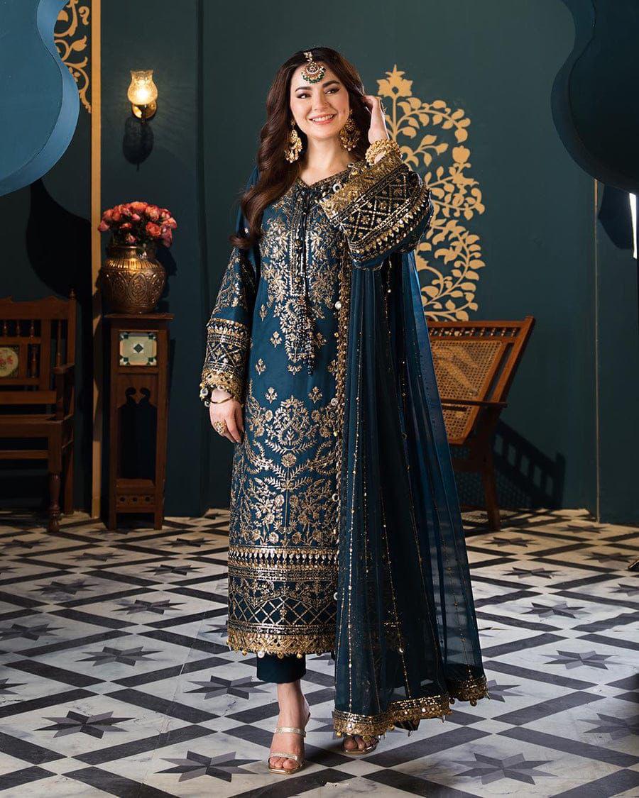 Woman in a traditional embroidered outfit standing in a decorated room with patterned floor and wall art.