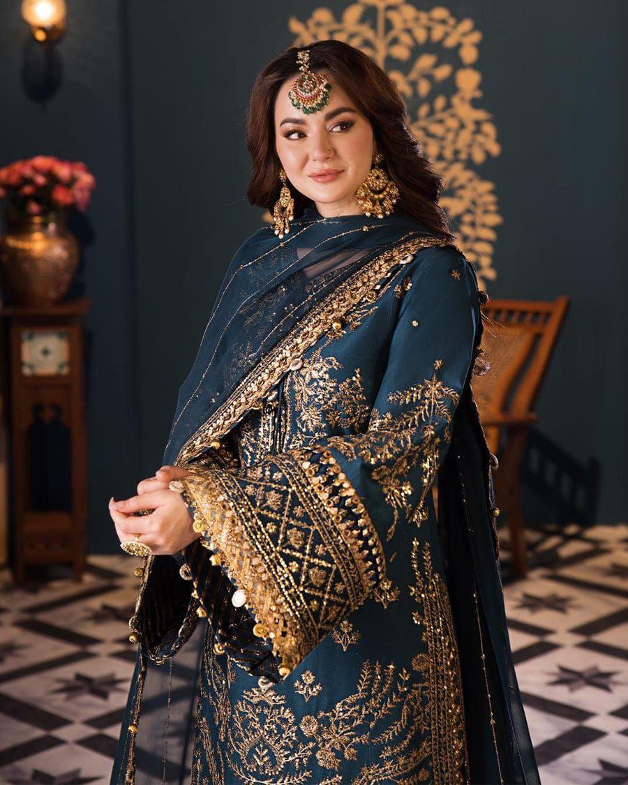 Woman in traditional embroidered outfit with gold details in a decorative room.