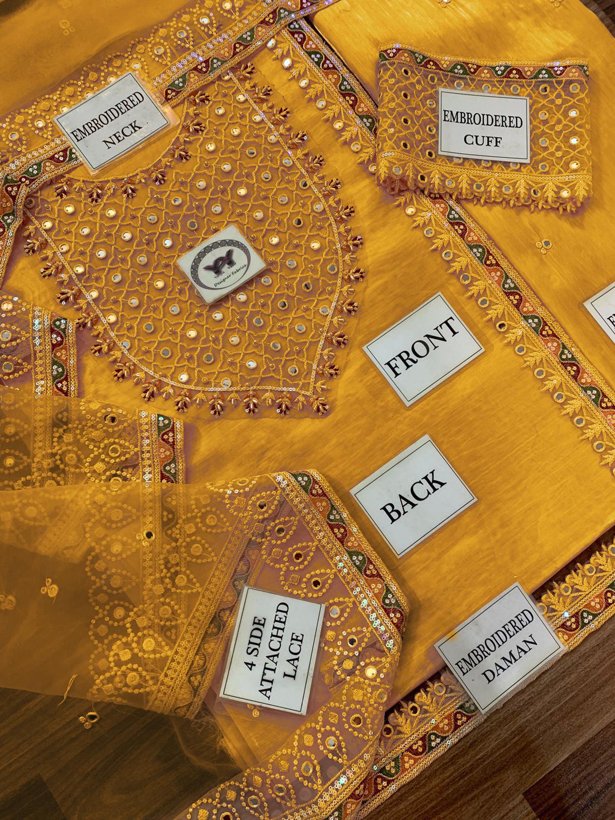 Embroidered yellow fabric with labels indicating design features on a wooden surface.