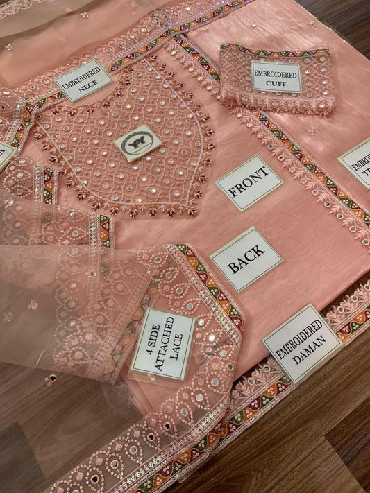 Detailed view of a pink embroidered garment with labeled parts on a wooden surface