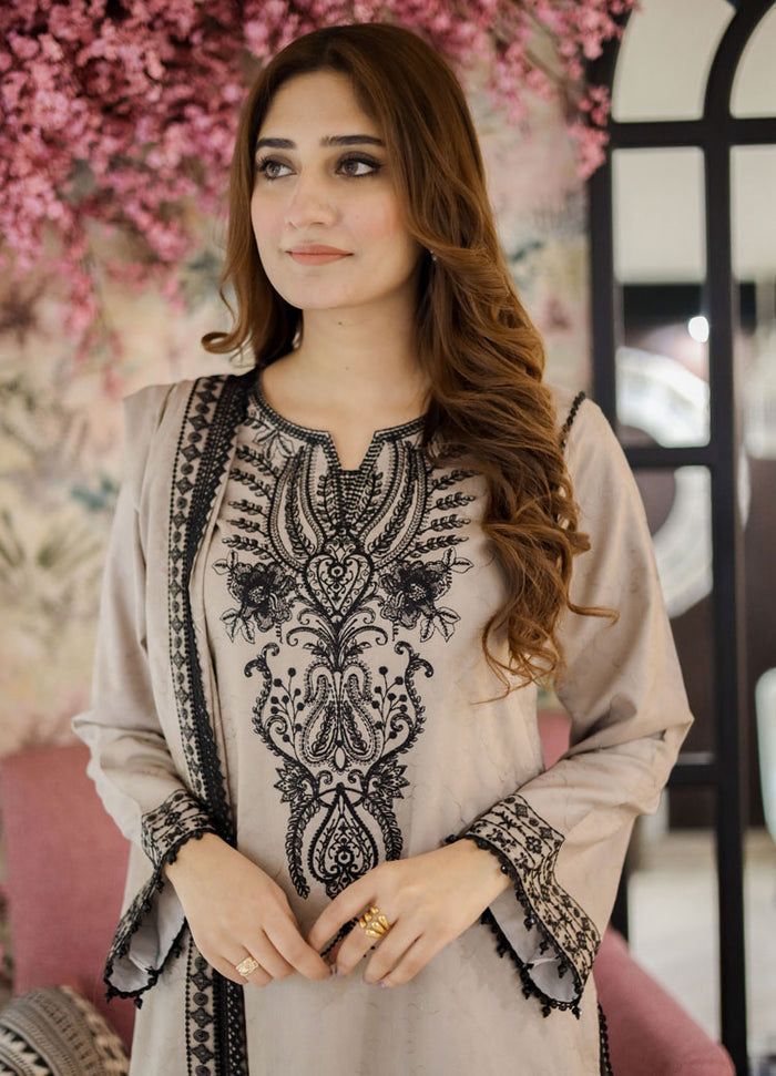 Woman wearing a beige and black embroidered dress with a blurred floral background