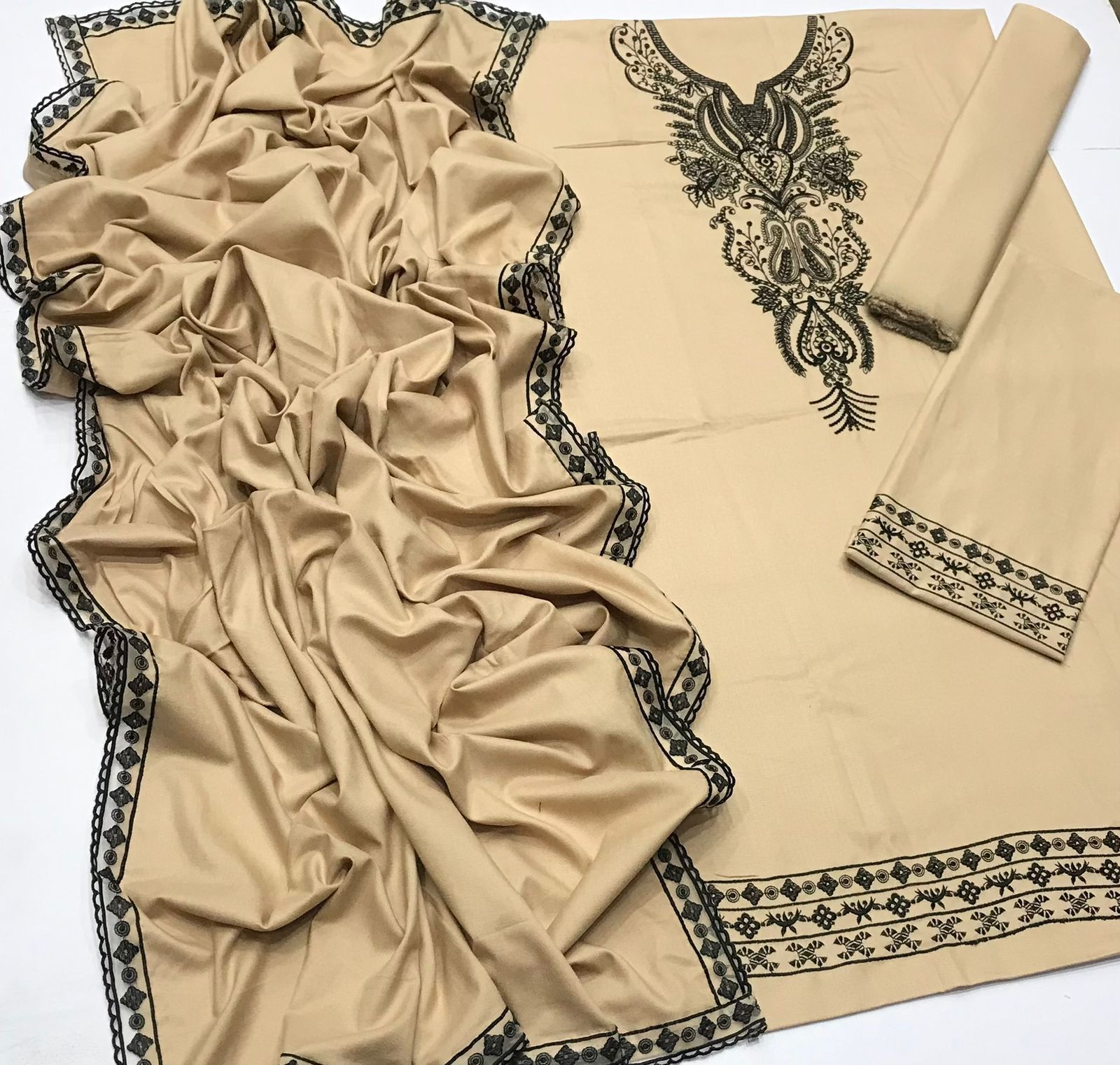 Beige fabric with black embroidery on a white background