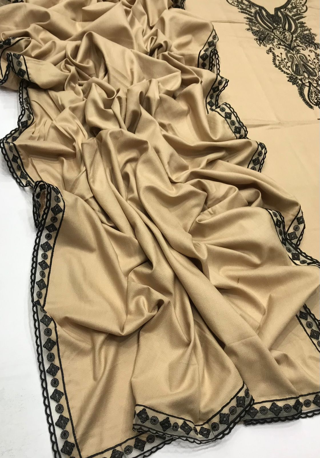 Beige fabric with black lace trim on a white background