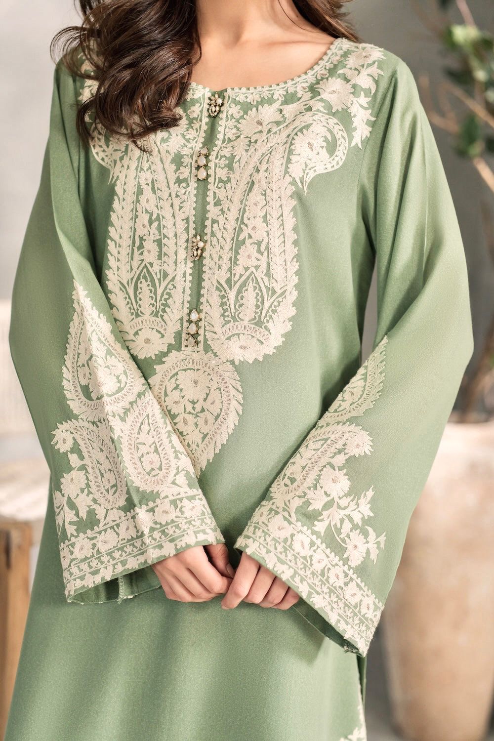 Green dress with intricate white embroidery on a neutral background