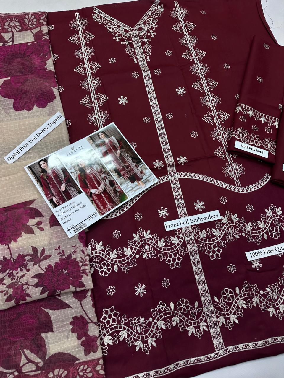 Maroon fabric with white embroidery and a printed material sample on a white background