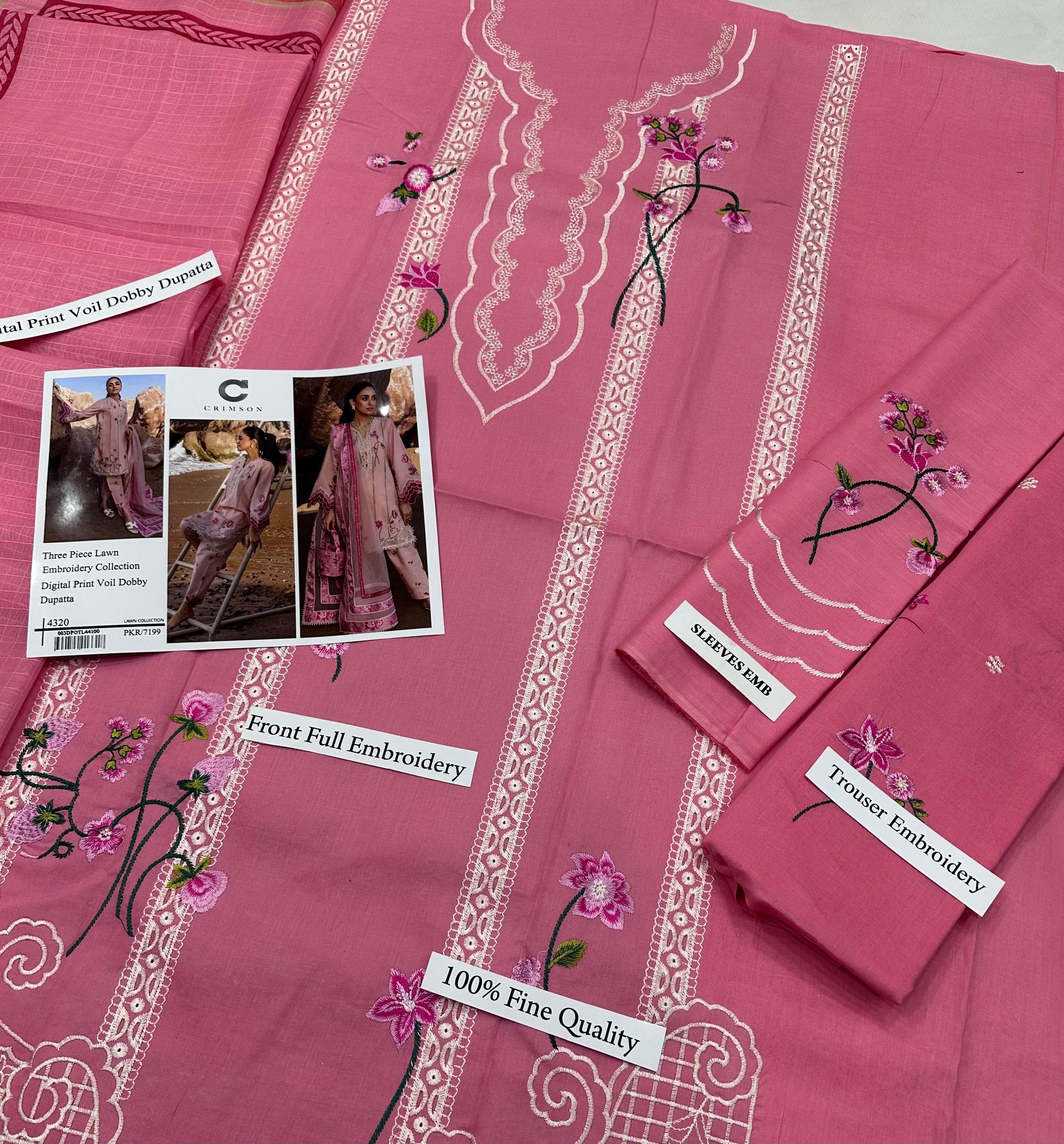 Pink embroidered fabric with floral designs and product labels on a pink background