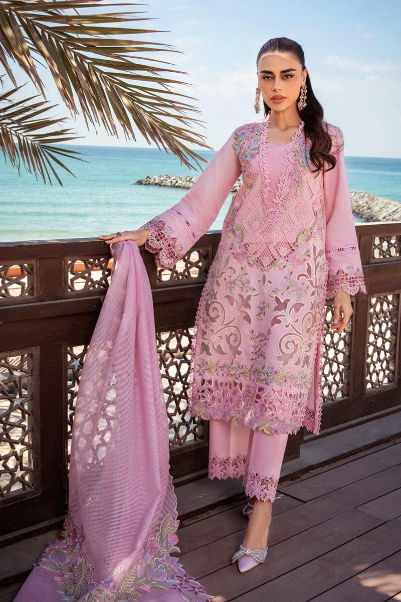 Woman in a pink embroidered outfit standing by a scenic ocean view.