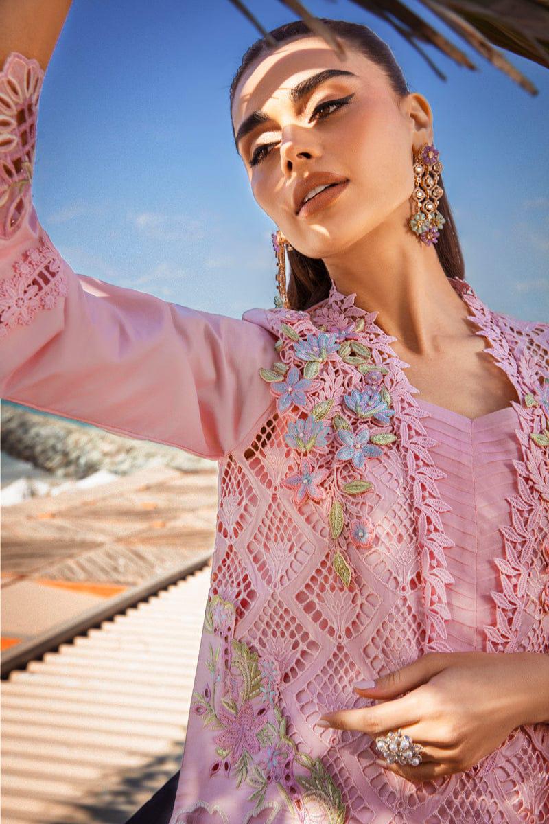 Woman wearing a pink embroidered outfit with floral details against a blue sky.