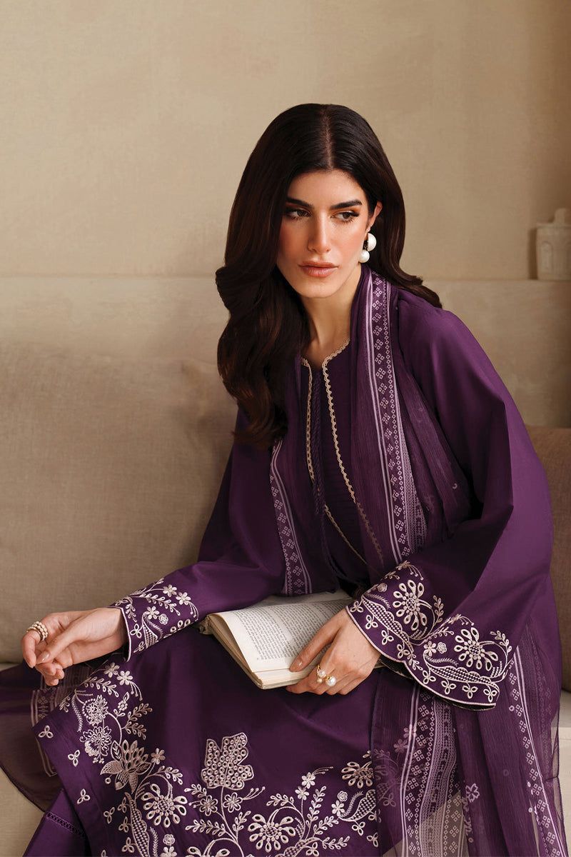 Woman wearing a purple embroidered dress sitting on a couch.