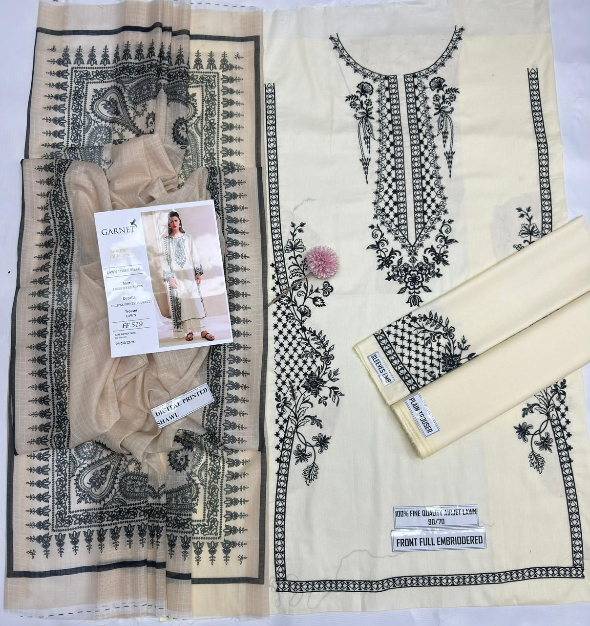 Fabric with black embroidery and a garment on a white background