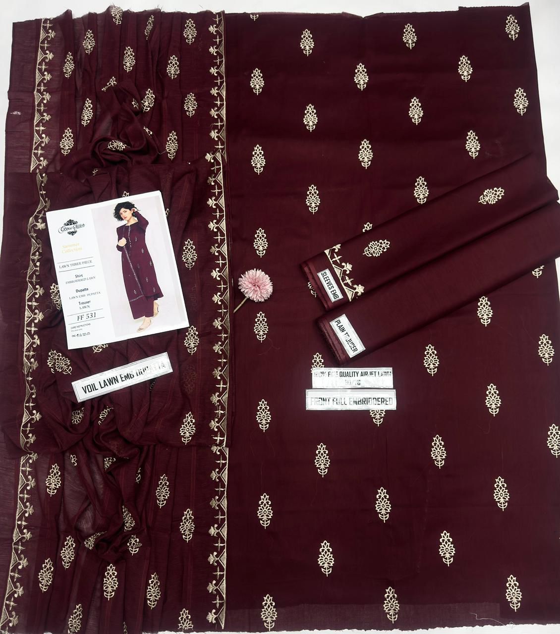 Maroon fabric with gold patterns and a dress model on a white background