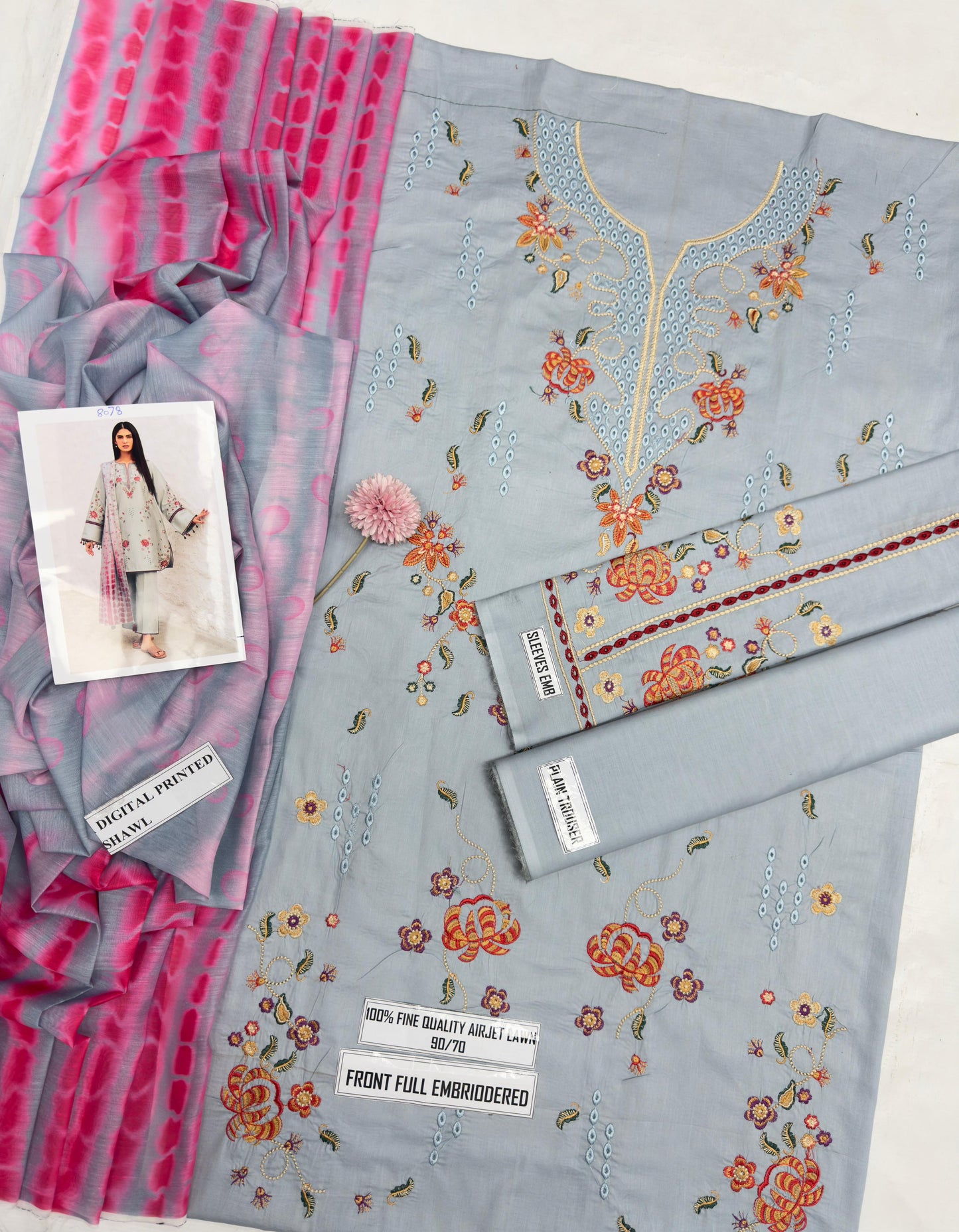 Embroidered fabric with floral patterns and a pink border, displayed on a white background.