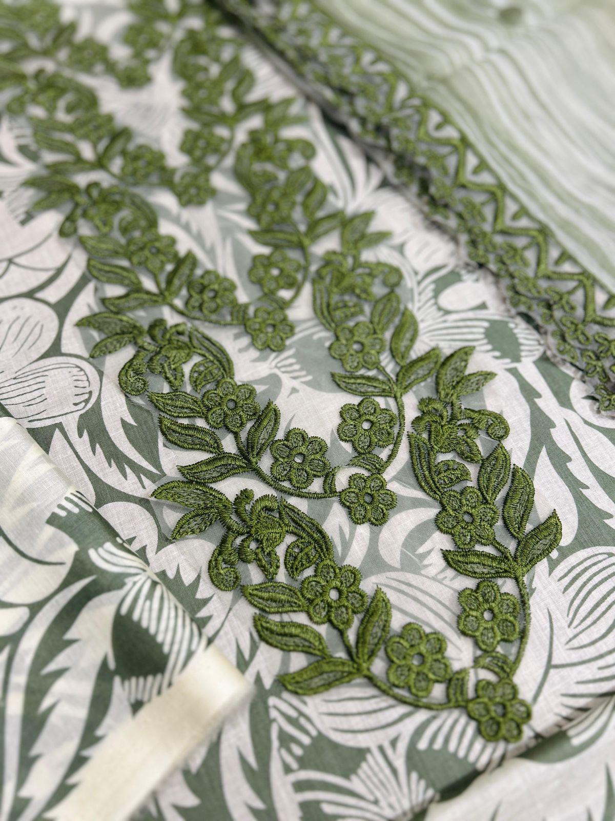 Close-up of green floral embroidery on fabric with a white background
