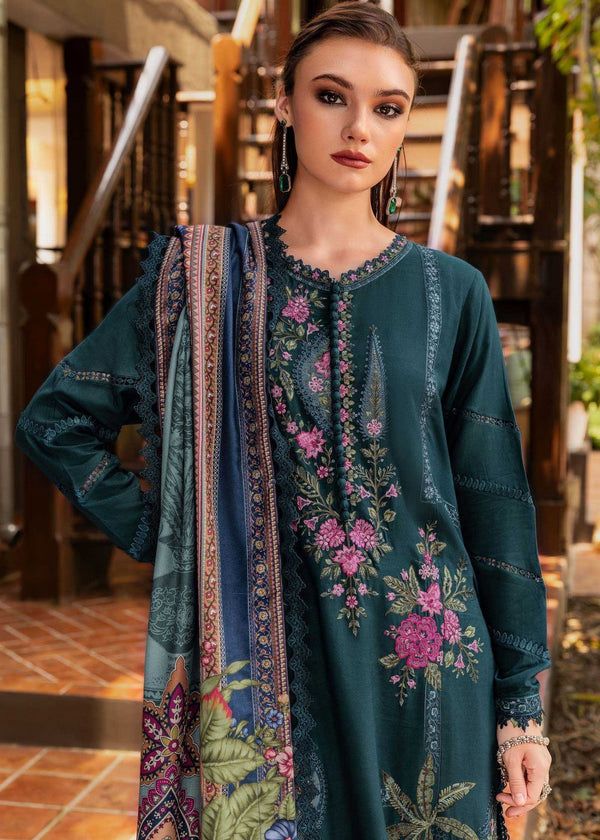 Woman wearing a teal embroidered dress with a colorful scarf in an indoor setting.