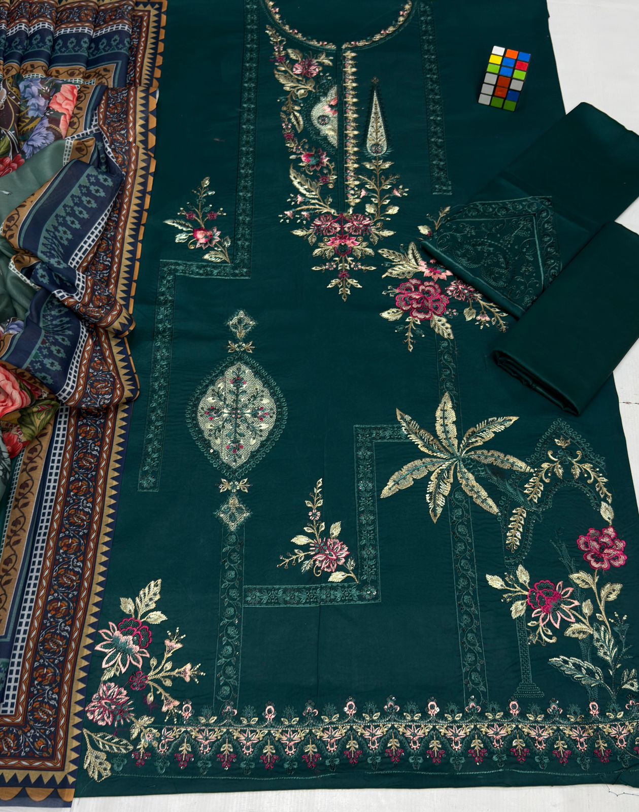 Dark green fabric with intricate gold embroidery on a white background