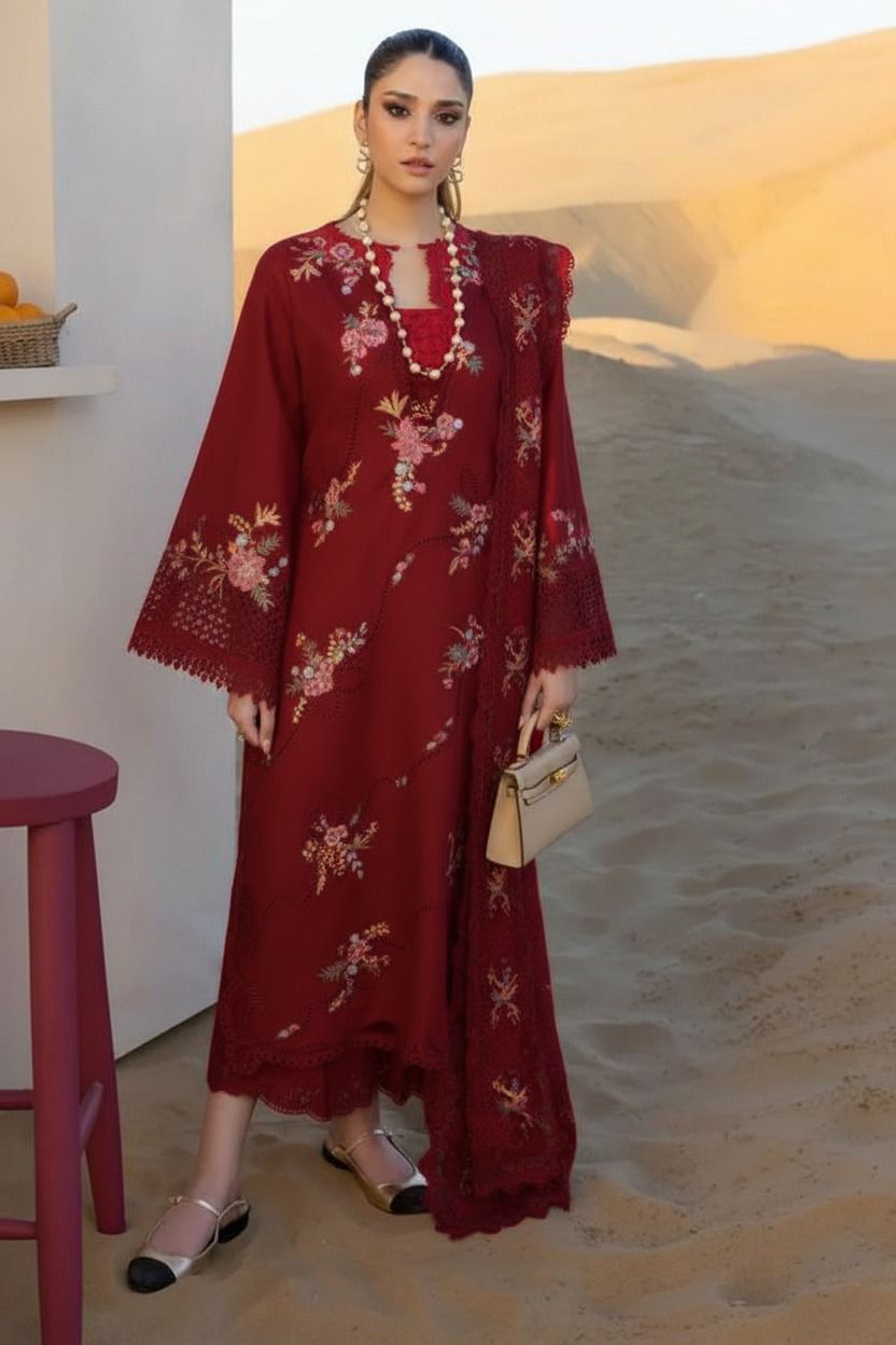 Woman in a red embroidered dress standing in a desert setting with sand dunes.