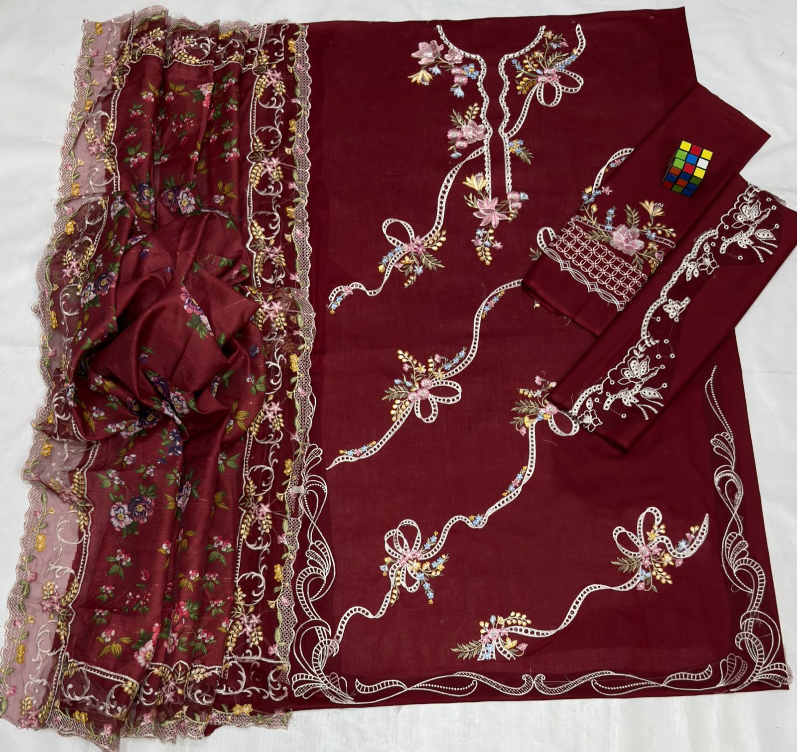 Maroon fabric with intricate floral embroidery on a white background