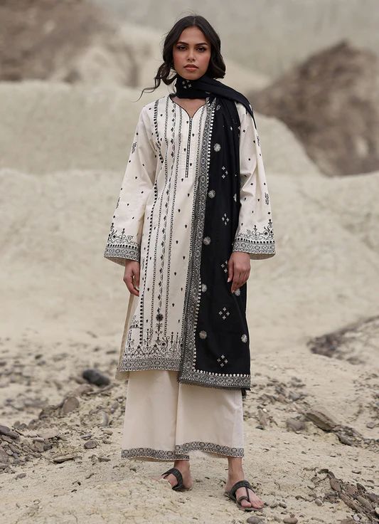 Woman wearing a traditional outfit with black and white patterns in a desert setting