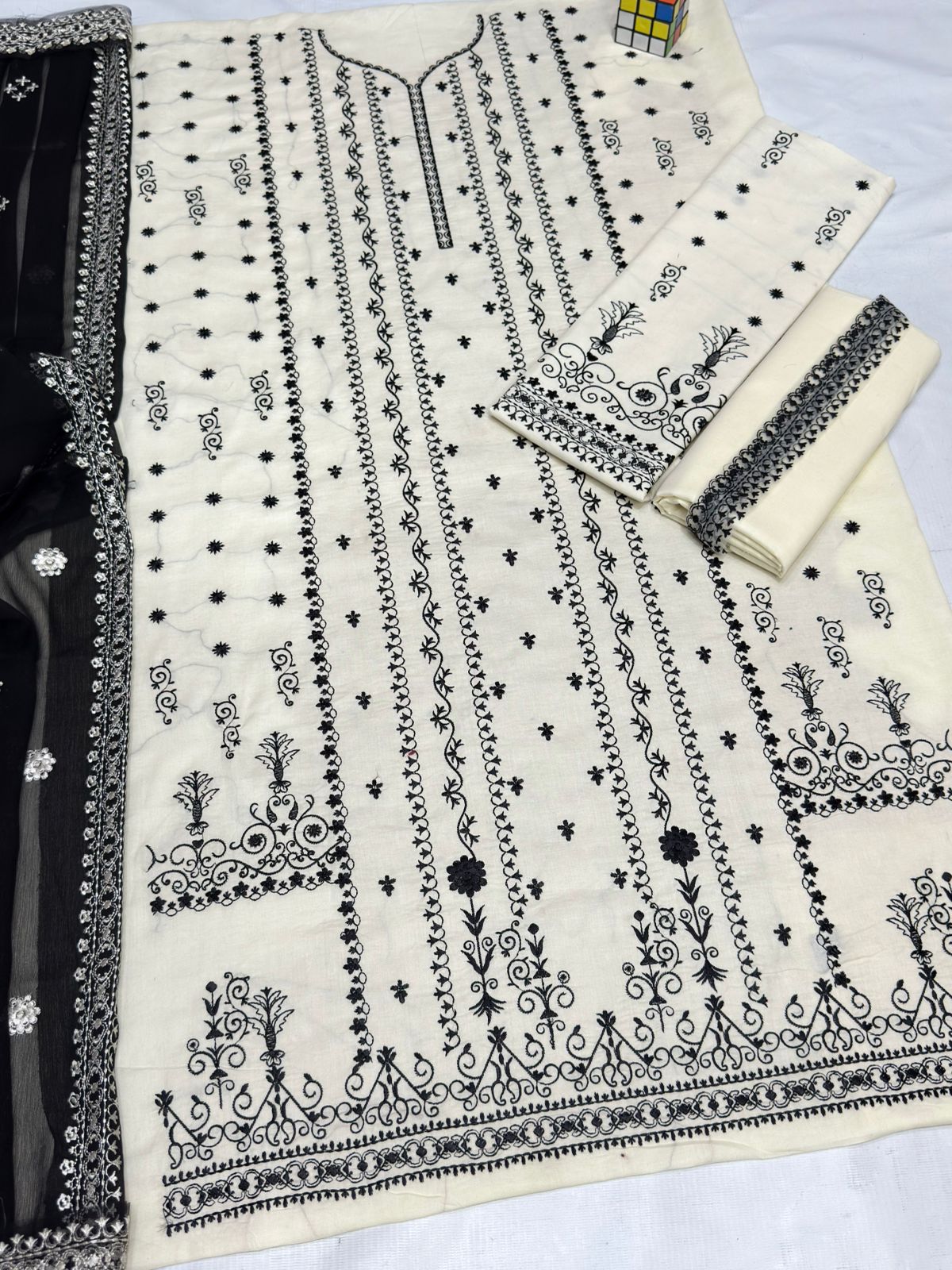 White fabric with black intricate embroidery on a white background