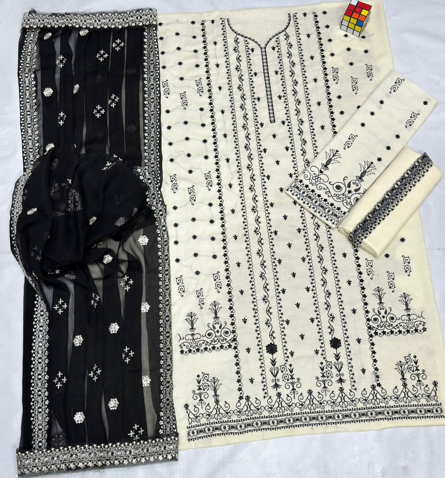 Black and white embroidered fabric with a black dupatta on a white background