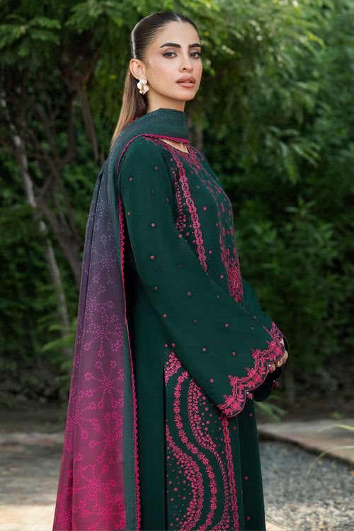 Woman wearing a green and pink embroidered traditional outfit with a blurred natural background