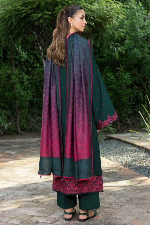 Woman wearing a green and red traditional outfit with a cape in an outdoor setting.
