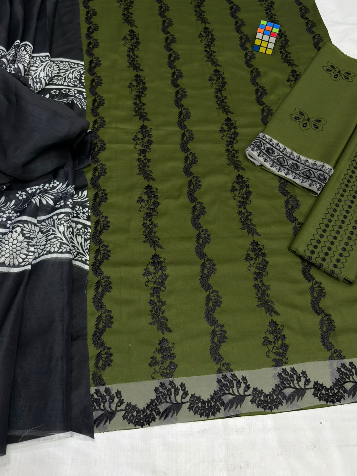 Green fabric with black floral patterns on a white background