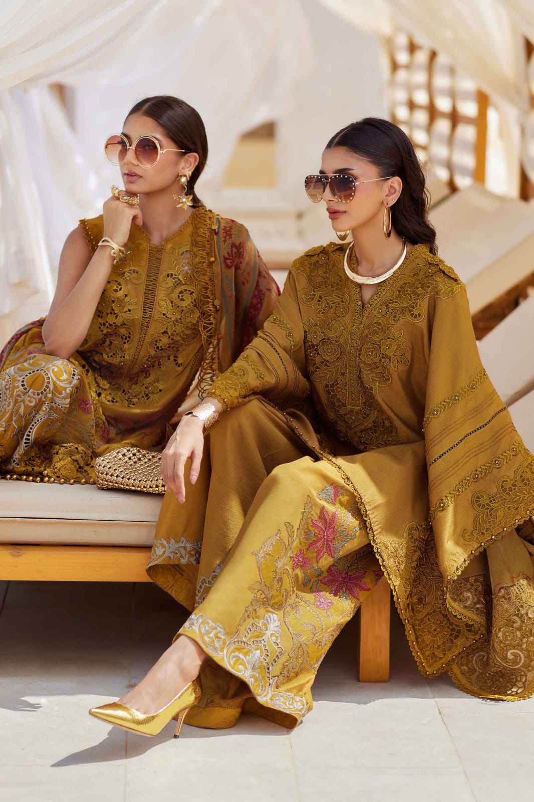 Two women in traditional embroidered outfits sitting on a sun lounger.