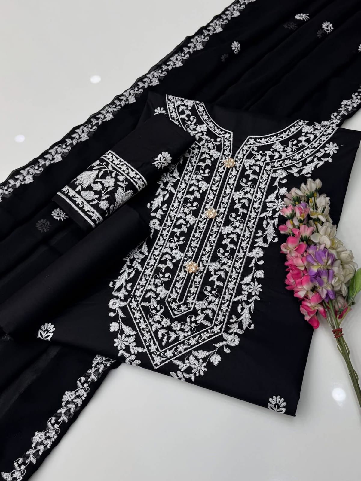 Black traditional outfit with white embroidery on a white background