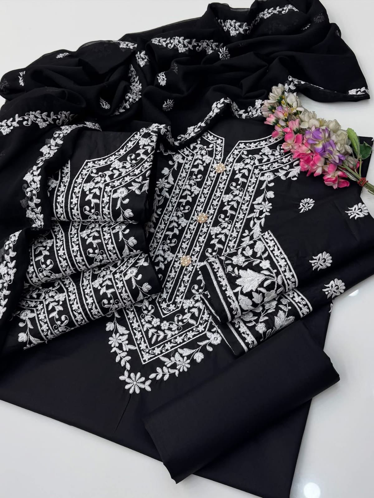 Black fabric with white embroidery on a white surface