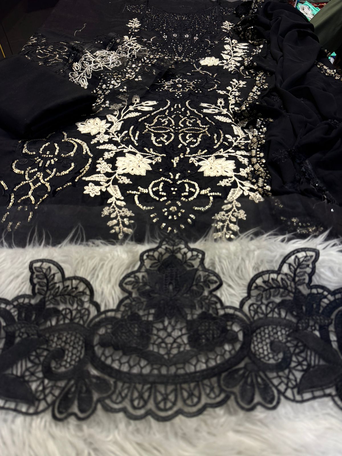 Black lace fabric with intricate white floral patterns on a textured surface