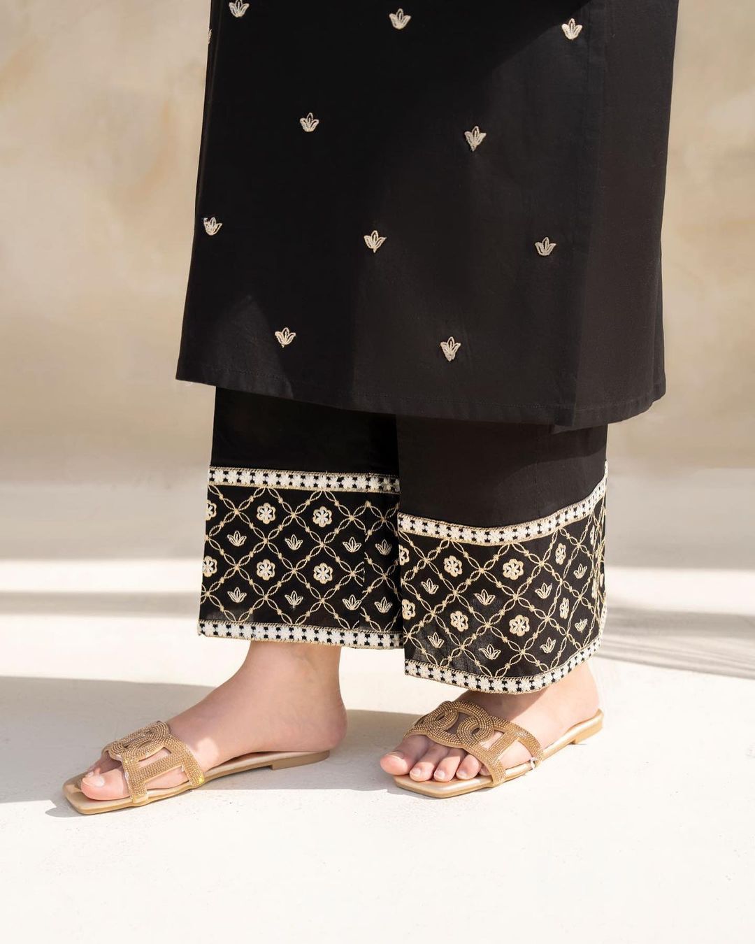 Black traditional outfit with white embroidery on a neutral background