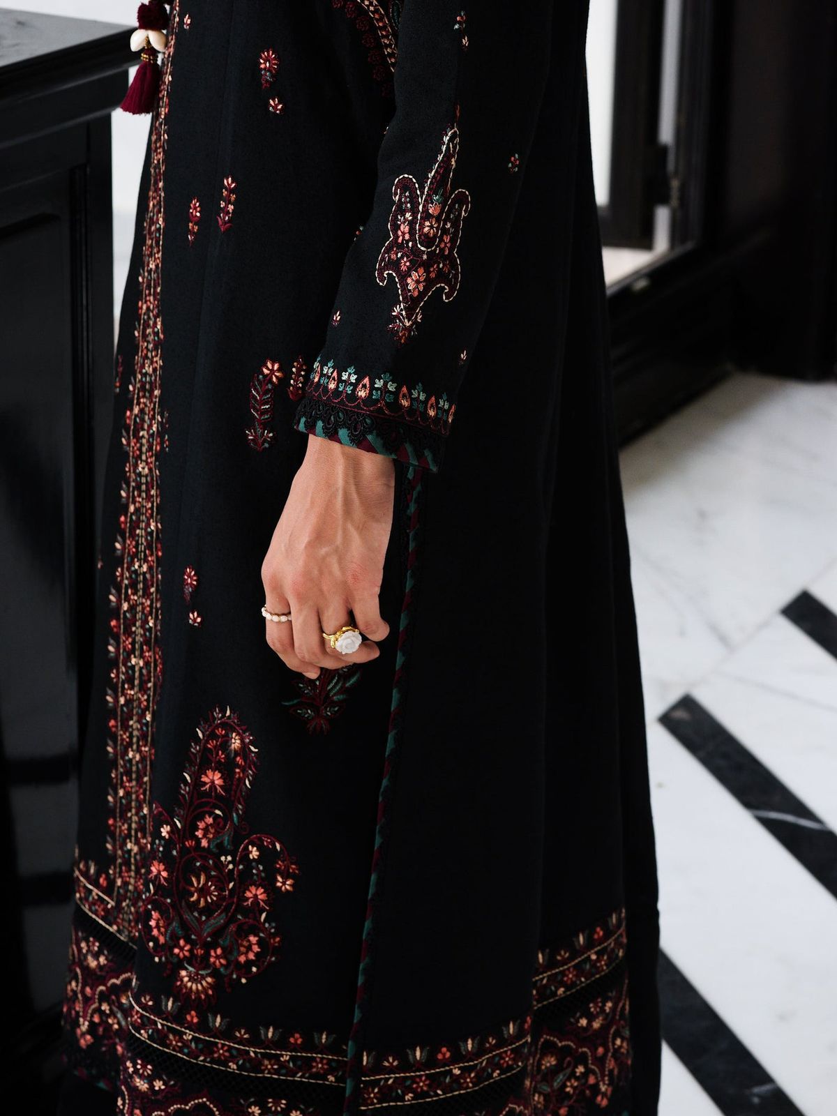 Black embroidered dress with floral patterns on a marble floor.