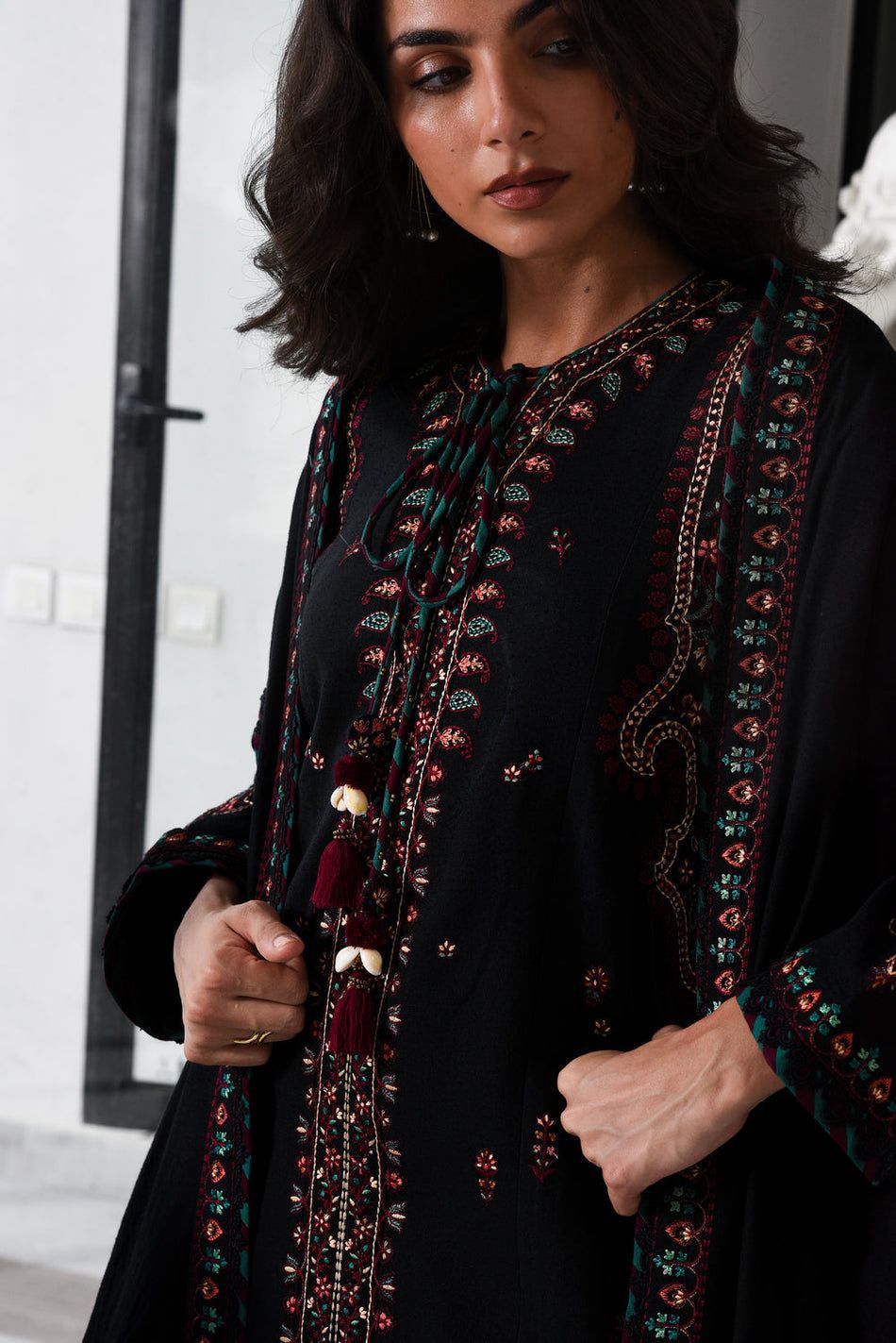 Woman wearing a black outfit with colorful embroidery in an indoor setting
