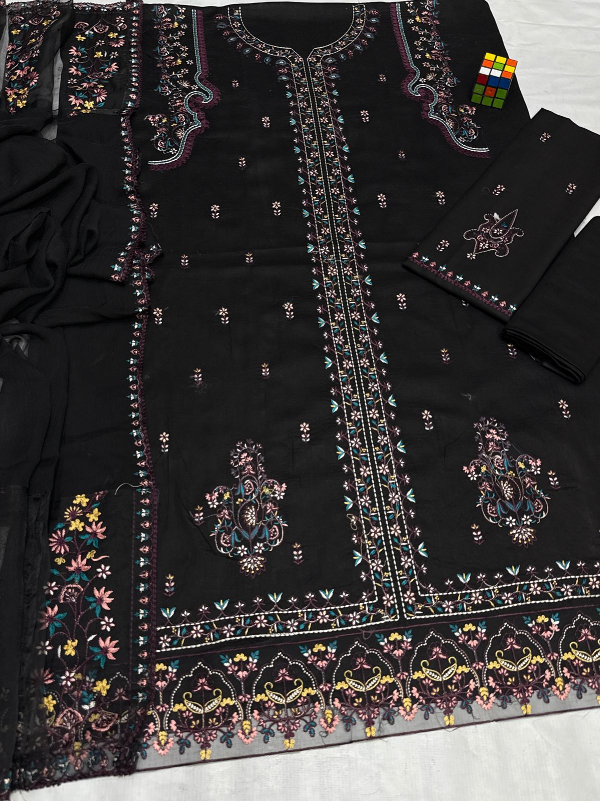 Black embroidered fabric with colorful patterns on a white surface