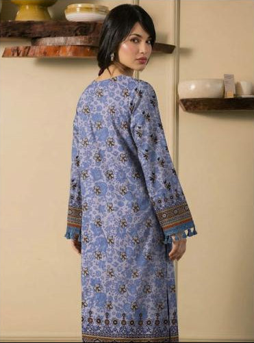 Woman wearing a blue floral embroidered shirt and pants with 'Ripple Collection' branding.