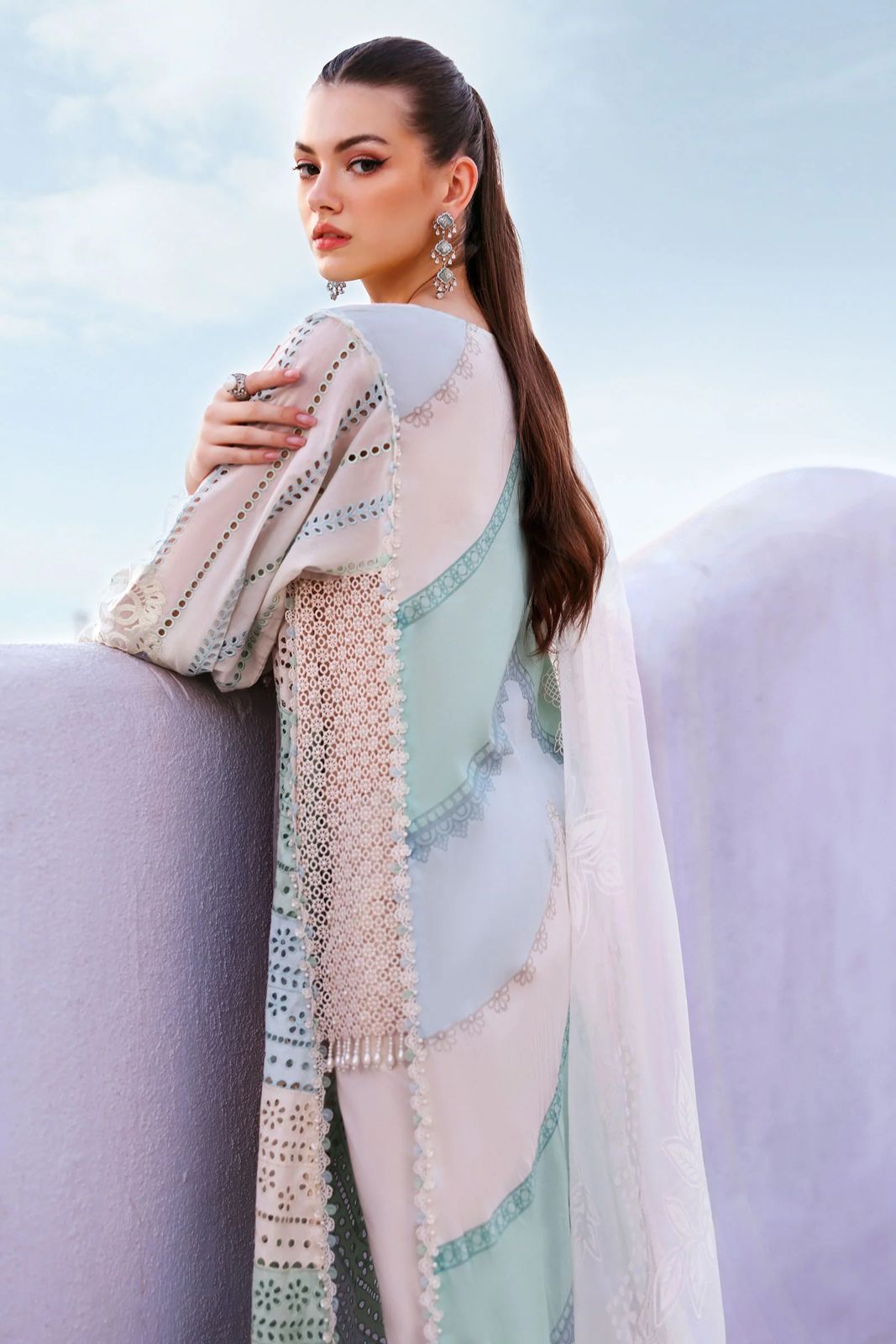 Woman wearing a patterned shawl against a light blue sky