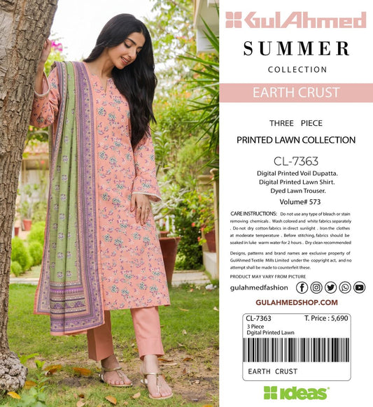A woman modeling a three-piece printed lawn collection outfit from KulAhmed Summer Collection, standing outdoors next to a tree. The outfit consists of a light pink printed kurta, matching trousers, and a green and pink patterned dupatta.